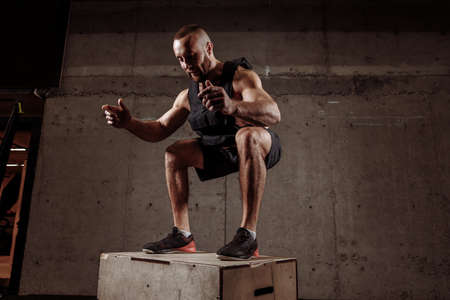 happy guy at the gym working out standing on a wooden squat box.strength training.の写真素材