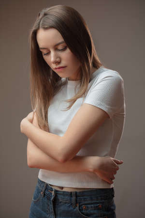 feeling of isolation. young helpless woman isolated on the brown background. girl suffering fron loneliness. grief concept. woman is of a solitary dispositionの写真素材