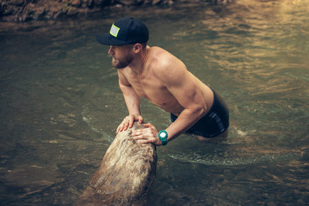 Athletic sportive man of european appearance swimming in mountain river during summer trip in...