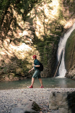 Tourist man relaxing, feeling hapyness and freedom when looking at beautiful waterfall in the national park forest at National Reserve Parkの写真素材