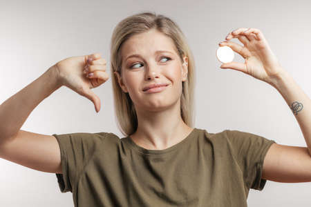 Human emotions and gestures concept. Attractive young woman with blonde hair bun having doubtful expression, shrugging shoulders in hesitation, tries to make difficult choice, confused about decisionの写真素材
