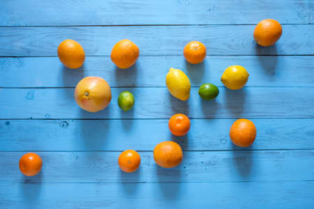 Whole citrus assorty of colourful fruits on the middle of blue wooden textured background. Top view. Copy space.の写真素材