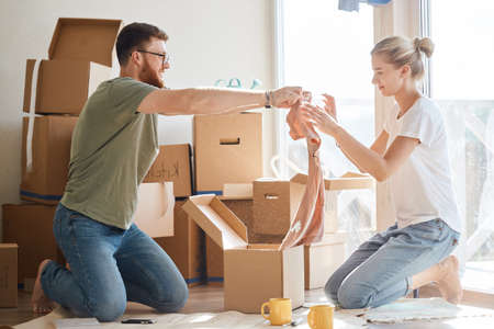 Young couple unpacking cardboard boxes at new home. Moving houseの写真素材