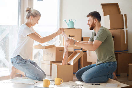 Young couple in new apartment unpacking cardboard boxesの写真素材