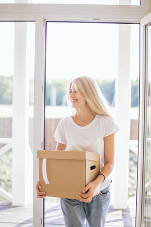 Happy smiling couple moving in new house and carrying carton boxes