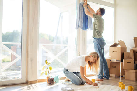 Young couple sitting at floor moving into new home looking at floor plans togetherの写真素材