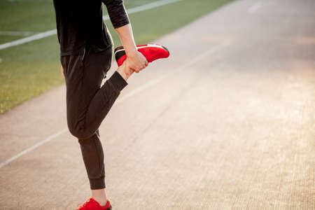man stretches body before running on race track in stadiumの写真素材