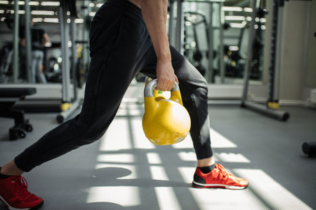 Caucasian handsome sportive man having functional fitness training with kettlebell in sport gym