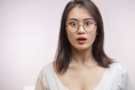 Shocked surprised Asian woman in optical eyewear, looking with unbelieving, terrifying expression or surprise. She is shocked with information.の写真素材