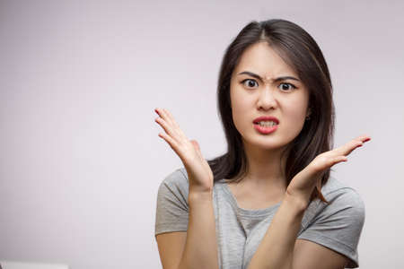 Portrait young angry Asian female unhappy, annoyed by something, isolated over white background with copyspace Human face expression emotion reactionの写真素材