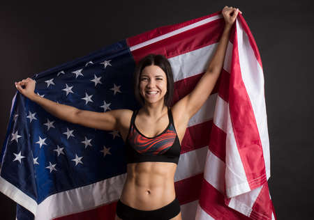 Happy sportswoman lifting widely American flag, concept of power and strength.の写真素材