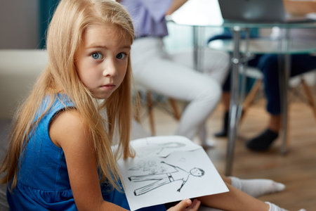 adorable caucasian child girl hold drawing of parents separated, they are going to be divorced....