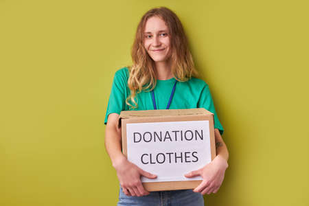 young caucasian woman holding a donate box with clothes, charity organisation concept, donation conceptの写真素材