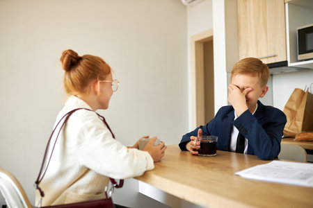 sad depressed kids have bad mood in the morning before going at work, sit drinking tea or coffee,...
