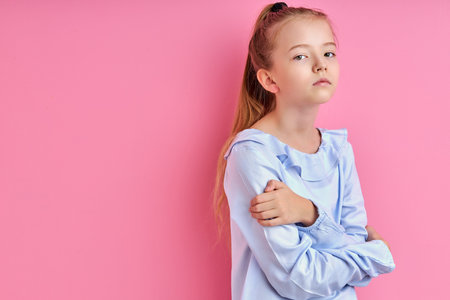sad sleepy girl looks detached , she is posing at camera, isolated on pink background