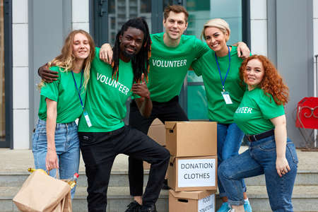 diverse volunteers packing, collecting humanitarian aid in donation box. multi-ethnic group of people working in charitable foundation helping in crises and homelessの写真素材