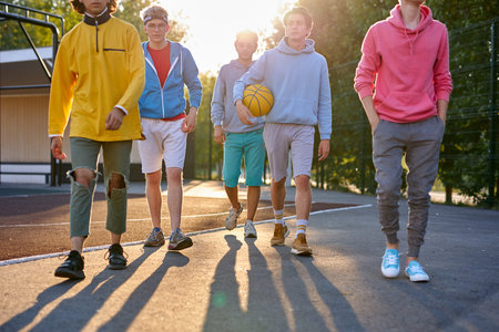 sportive young boys going to play basketball in the street, handsome teenagers have friendly talk...