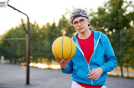 portrait of serious young caucasian boy with basketball ball in hands, handsome guy in eyeglasses...