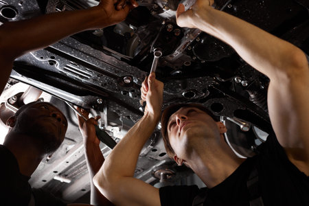 two friendly professional auto mechanic during work, they are successfully repairing car, solve...