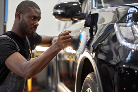 hard-working auto mechanic worker polishing car at automobile repair service, renew service station...