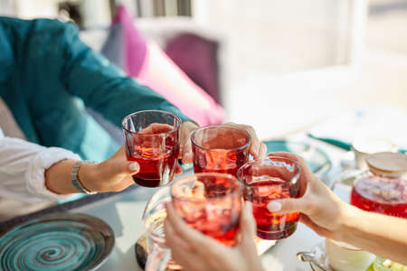 group of happy friends celebrating in cafe, they clink glasses with sweet beverages, leisure, celebration, drinks, people and holidays conceptの写真素材