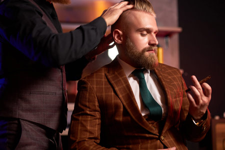 confident male hairstylist cut hair to elegant stylish man sitting in salon, young male enjoy the...
