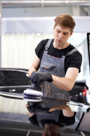 repairing in action. hardworking guy employee in uniform works in the automobile salon, confident...