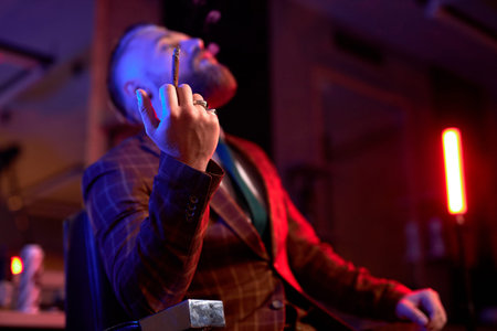 rich young caucasian business man in suit smoke a cigar while sitting alone in dark room, enjoy,...