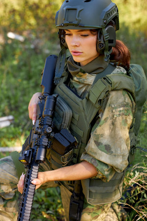 attractive brave military woman with a gun in forest, survival in wild forest, caucasian female in...