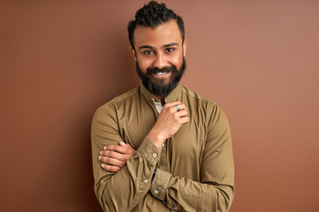 indian arab ith a happy and cool smile on face isolated on brown o background. portrait of lucky...