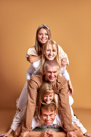 portrait of happy group of caucasian youth having fun in studio with brown background, beautiful people in trendy wear are cheerful. models, people, emotions conceptの写真素材