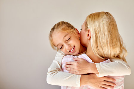 little girl hugging mother, friednly parent calm down her loving daughter, at homeの写真素材