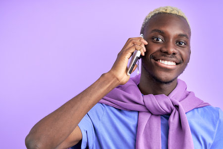 nice pleasant black man talk on phone isolated in studio on purple background, smile, listen to interlocutorの写真素材