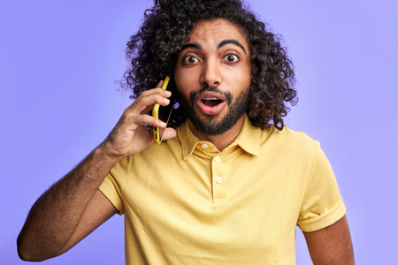 man is surprised by talk, sharng news with friends while talking on phone, look at camer with opened...