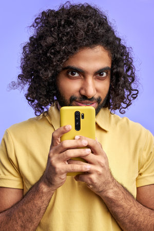 man use mobile phone, hold it near face, look at camera hiding something, secret messageの写真素材