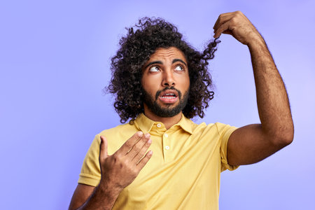 funny arabic man is thinking about barber. need to cut long hait, looking at split endsの写真素材