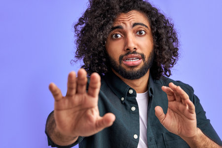 man has panick attack. young arab man is terrified with fear expression stop gesture with hands, in shock. panic concept.の写真素材