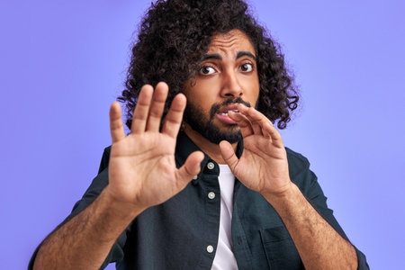 male is panicking. young arab man is terrified with fear expression stop gesture with hands, in shock. panic concept.の写真素材