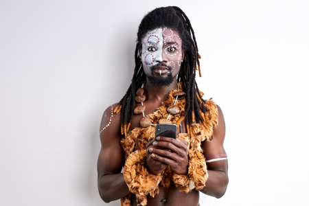 tribal man is surprised by something he saw in smartphone, young male in native national wear look...