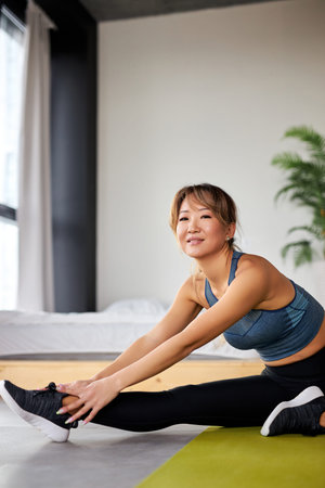 woman in sportswear doing fitness stretching legs, exercises at home in bright room. sport, healthy...