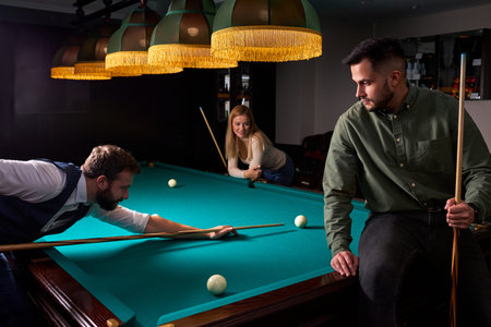 two young male friends came to play sport game billiards or snooker, in the dark club after work