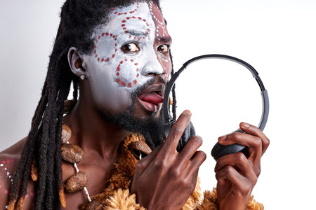 african native man tastes headphones, licks it, use it incorrectly. male in ethnic aborigen wear...