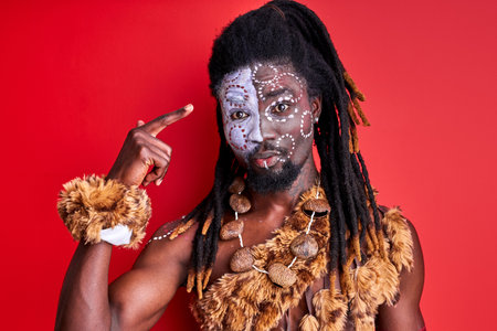 african man in ethnic wear ointing finger at head, stand in shock, talking something, isolated over red backgroundの写真素材