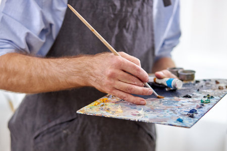 artist mix colors on palette holding in hand close up. creativity, art conceptの写真素材