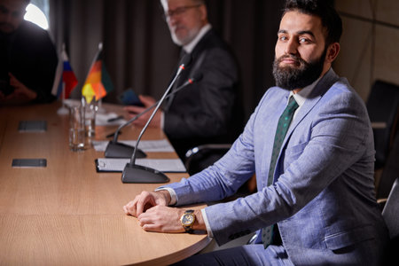 arabic male in suit sits at desk posing looking at camera, handsome smiling male executive satisfied...