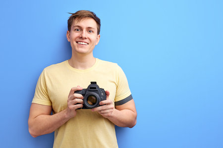 male photographer holding professional camera in hands and smiling at camera, take photo. smiling...