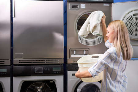 Young female getting out clean clothes from washing machine, people lifestyle concept. cleaning, washingの写真素材