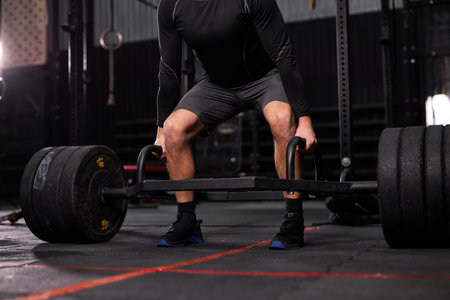 cropped bodybuilder guy prepare to do exercises with barbell in dark modern fitness center or gym.bodybuilders hand is liftingbarbell and exercising, alone, man dressed in sportive clothesの写真素材