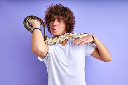 friendly male holding snake in hands, doesnt afraid, no phobia. caucasian male in white t-shirt posing with snakeの写真素材