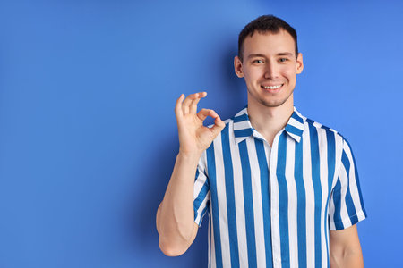 Cheerful man showing OK gesture and smile.